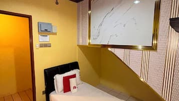 Een kamer met een bed, een televisie aan de muur, een deur en een lamp.