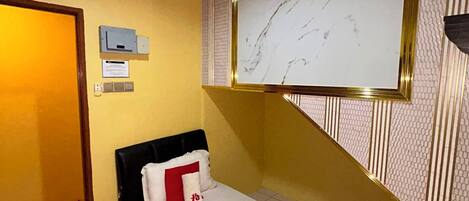 Una habitación con una cama, un televisor montado en la pared, una puerta y una lámpara.