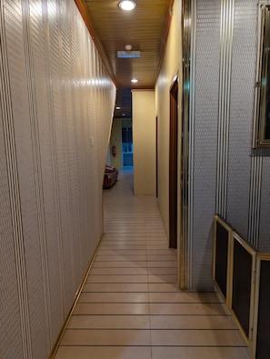 A hallway with patterned walls, a tiled floor, and a ceiling with recessed lighting.