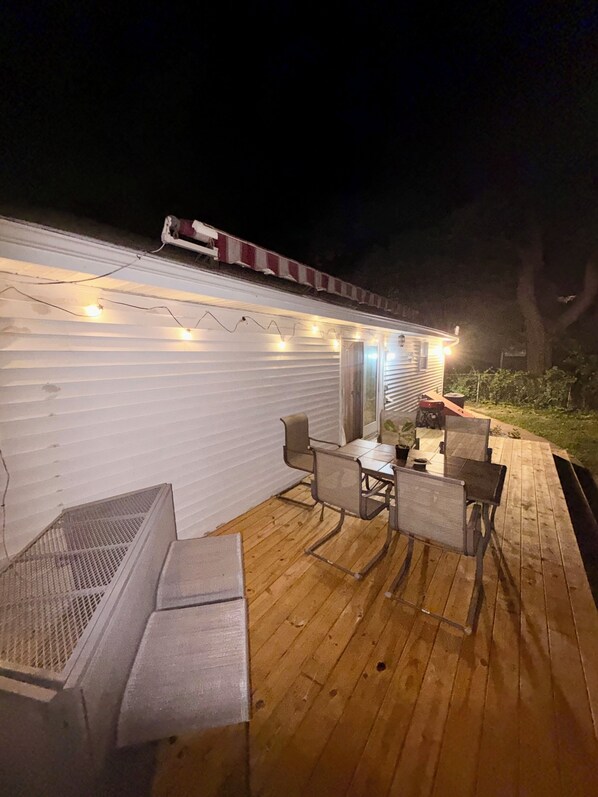 An outdoor deck with a table and chairs, a fire pit, and string lights.