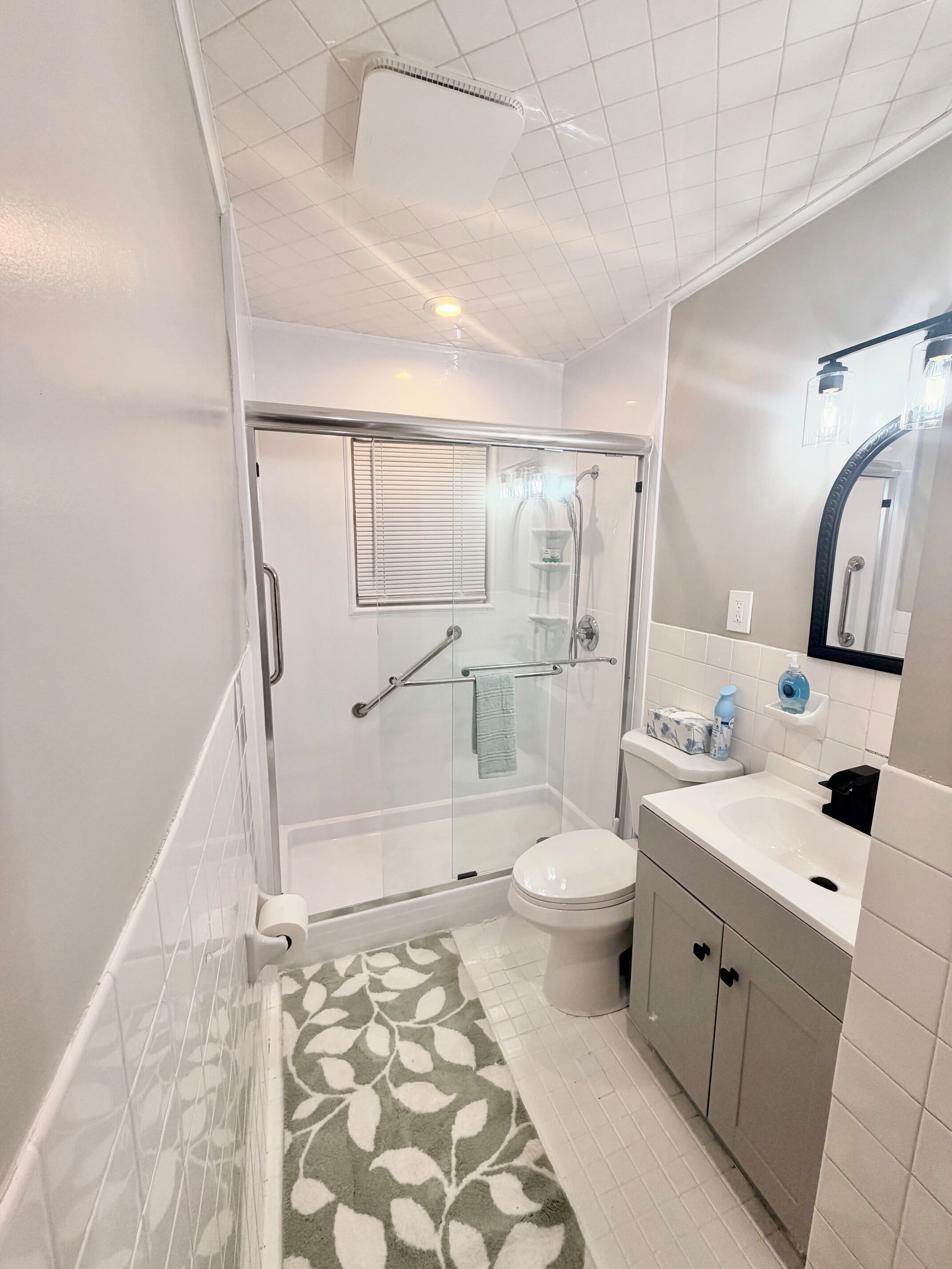 A bathroom with a glass-enclosed shower, a toilet, a sink, and a mirror.