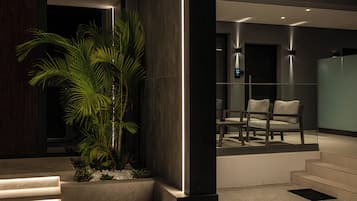 A modern interior with a staircase leading to a seating area, a large plant, and a digital display.
