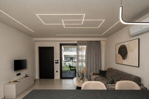 A modern living room with a flat-screen TV, a sofa, a coffee table, and a dining table.