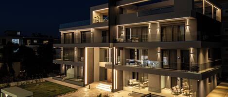A modern multi-story building with balconies, large windows, and a well-lit outdoor area.