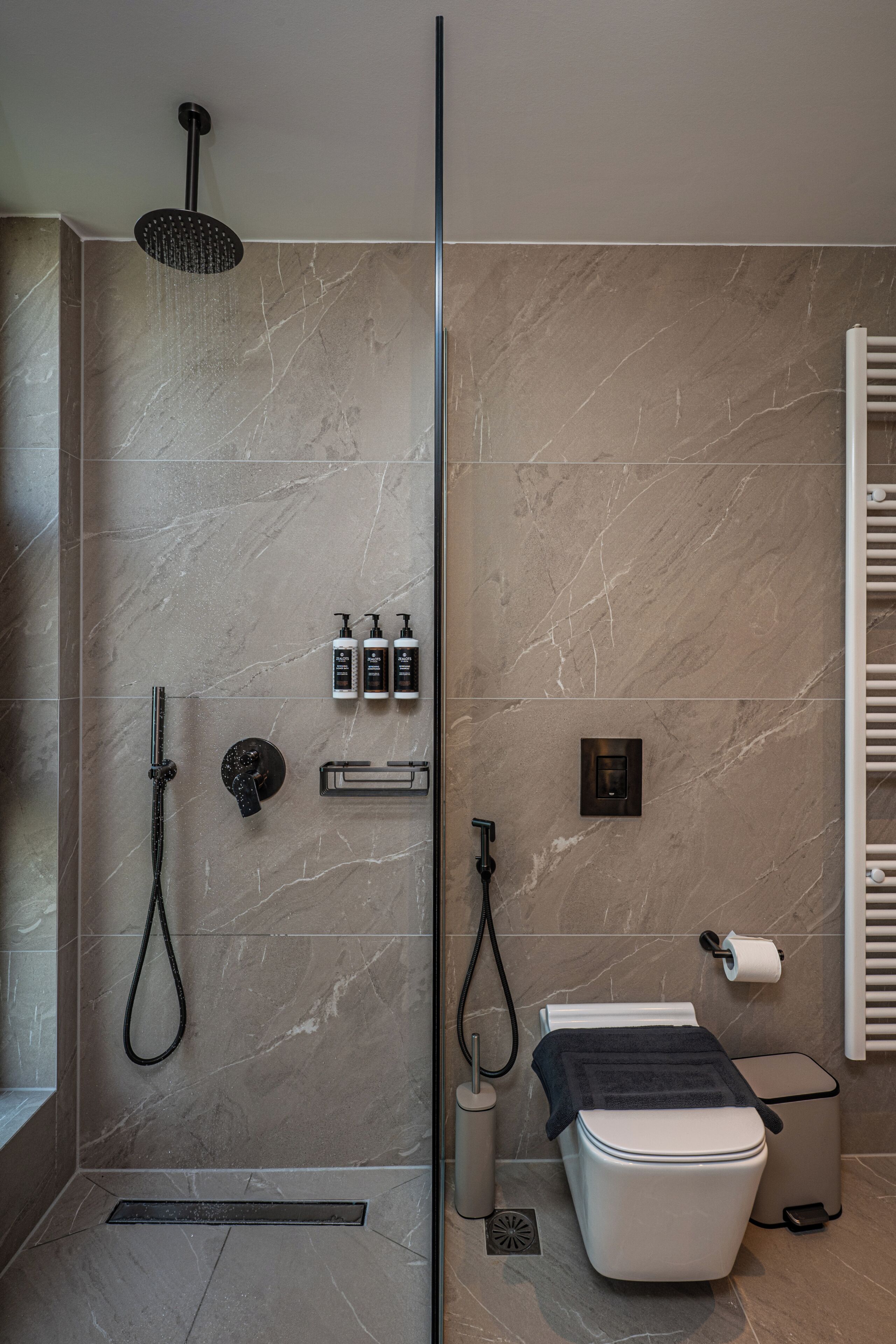 Et moderne badeværelse med bruser, toilet og håndklædetørrer.