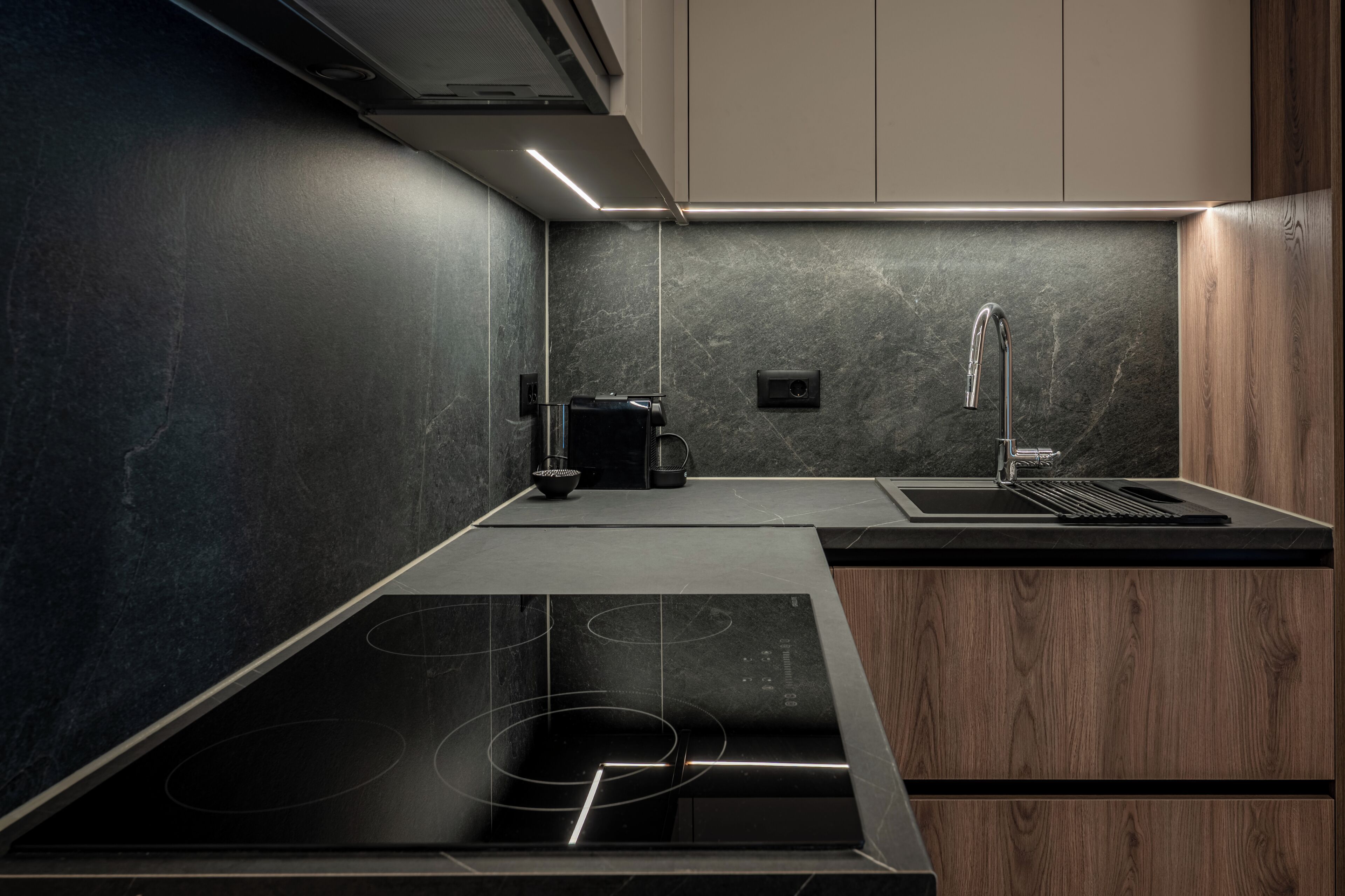 A modern kitchen with a built-in stove, a sink, and a coffee machine.