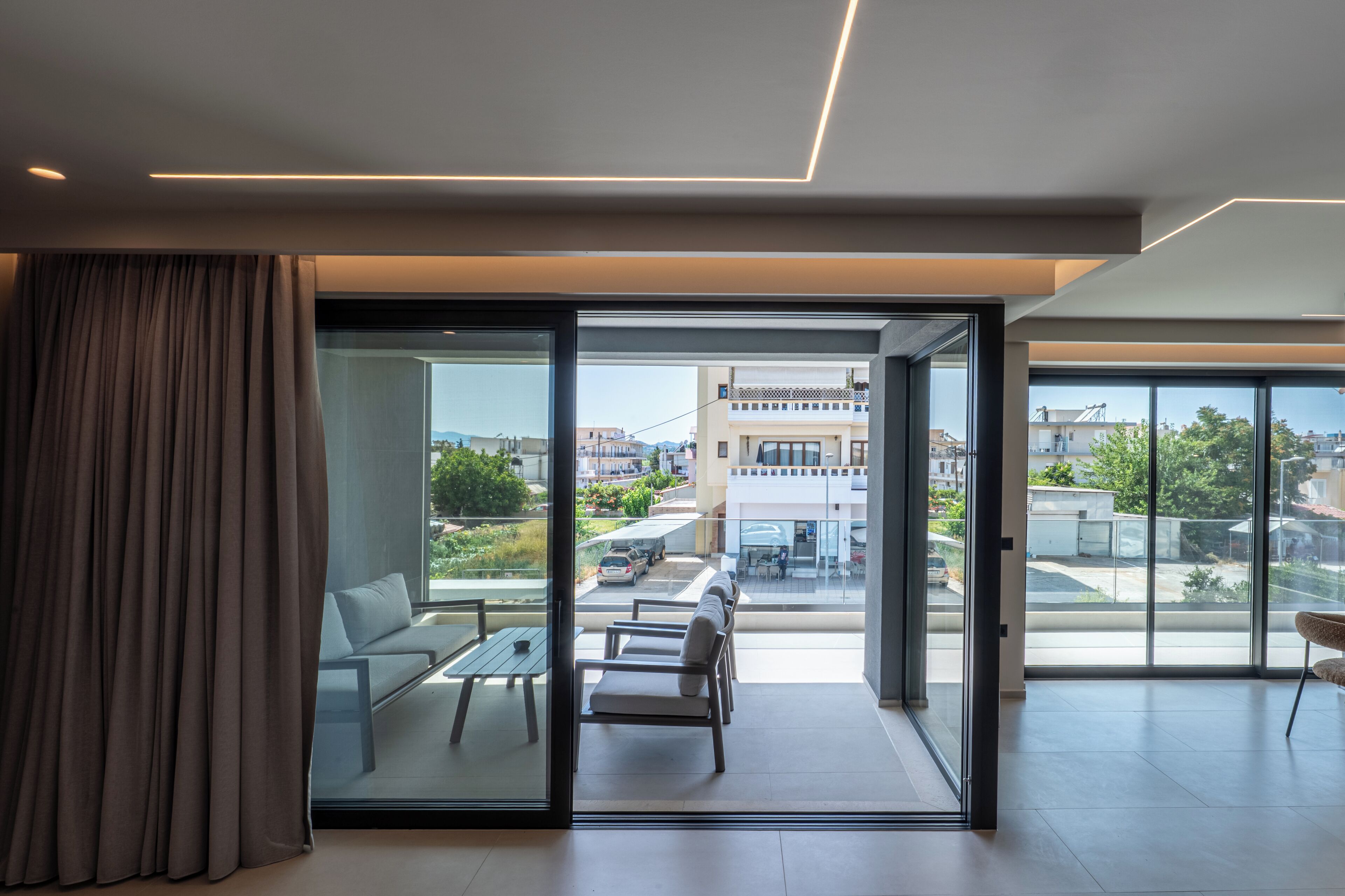 Una sala de estar moderna con un amplio ventanal corredero que da a un balcón exterior.
