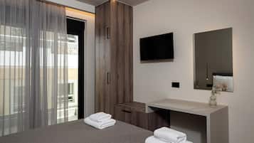 Un dormitorio moderno con cama, armario de madera, televisor y tocador de baño.