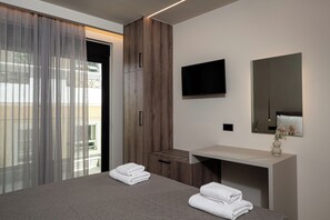 Un dormitorio moderno con cama, armario de madera, televisor y tocador de baño.