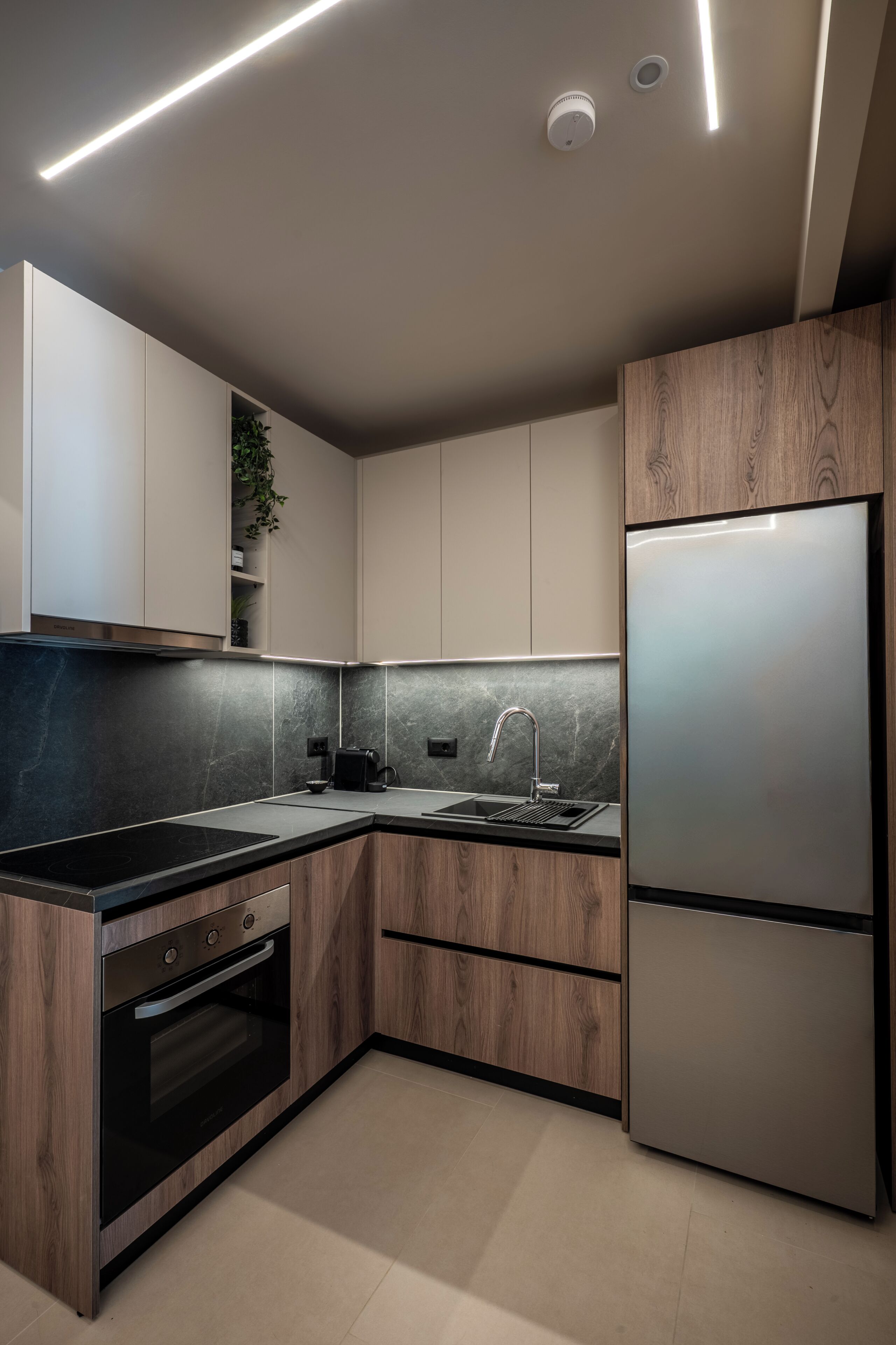 A modern kitchen with built-in appliances, a black countertop, and wooden cabinetry.