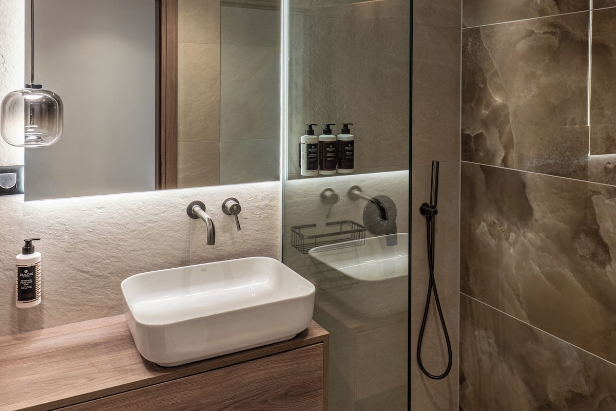 Signature Experience Suite | Bathroom | Hair dryer, slippers, towels, soap