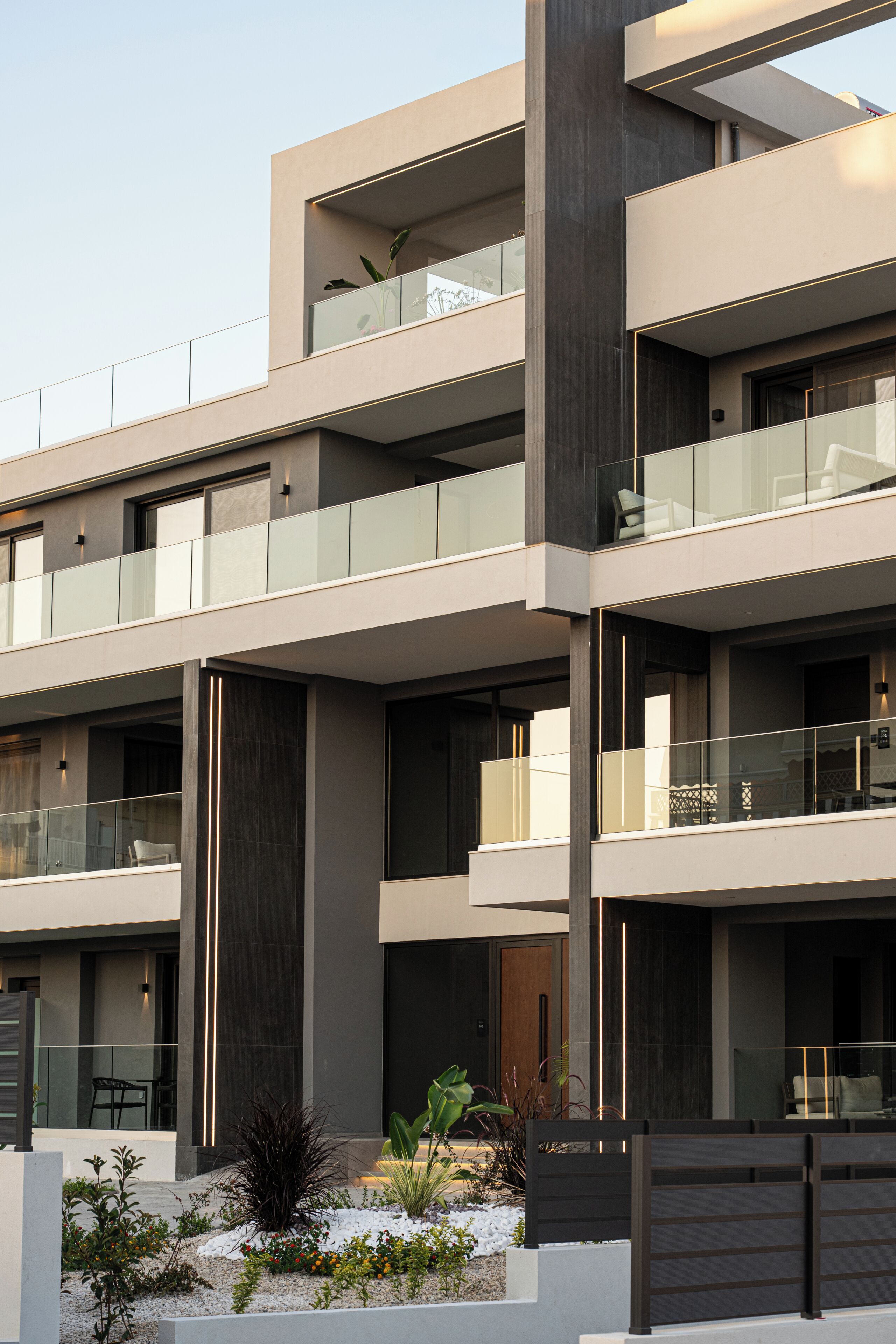 A modern multi-story building with balconies, large windows, and a minimalist design.