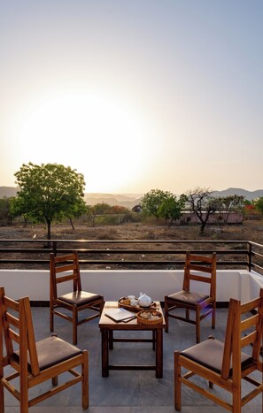 Eine Terrasse mit Tisch für zwei Personen, mit Blick auf eine Landschaft mit Bäumen und Hügeln in der Ferne.