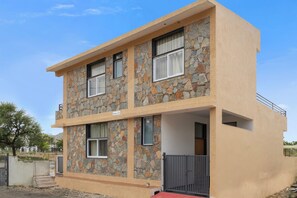 A two-story building with a stone facade, multiple windows, and a gated entrance. - ELIVAAS Signature Hiara Rudraksha 6BHK  (Udaipur)