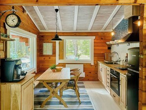 Een keuken in blokhutstijl met houten wanden, een centraal eiland en een hangende lamp.