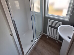 A bathroom with a glass shower enclosure, a white sink, and a radiator. - Haven Seashore, Ellerton Willerby Xtra (Great Yarmouth)