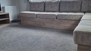 Ein Wohnzimmer mit grauem Sofa, einem Holztisch und einem grauen Teppich.