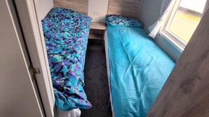 Ein kleines Zimmer mit zwei Betten, einem Fenster und einer Tür.