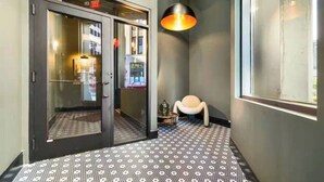 A hallway with a patterned floor, a door with glass panels, and a hanging light fixture. - Comfortable 2BR — Conveni (Pittsburgh)