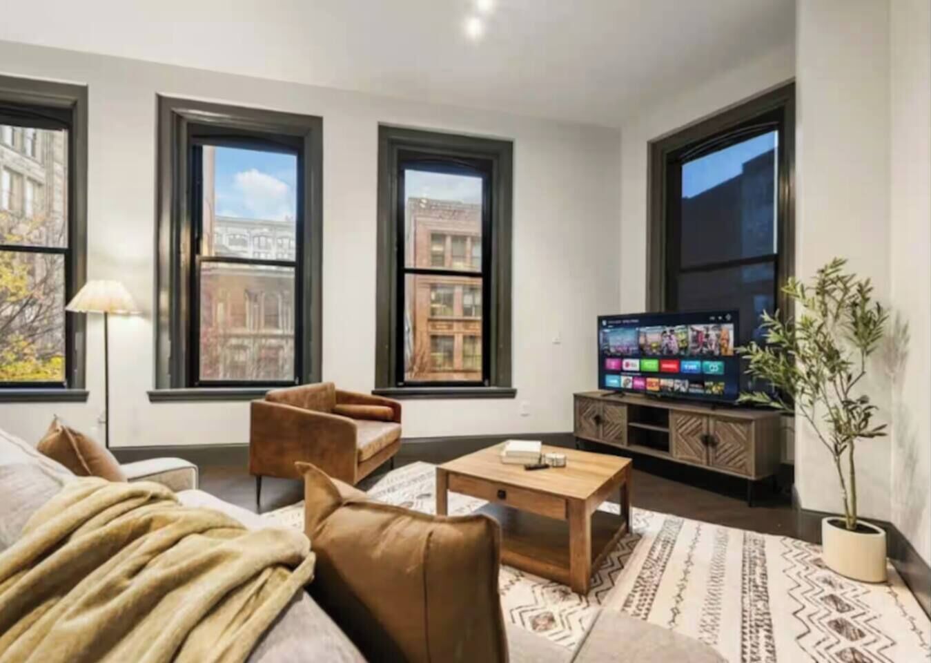 Bright city-view living room with large windows and smart TV
