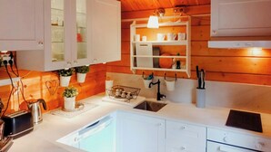 Eine Küche mit weißen Schränken, einem Spülbecken, einer Arbeitsplatte mit Wasserkocher und einer Pendelleuchte.
