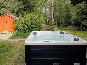 A hot tub in a natural setting with a wooden shed in the background. - Log cabin with hot tub and nature right outside (Ryd)