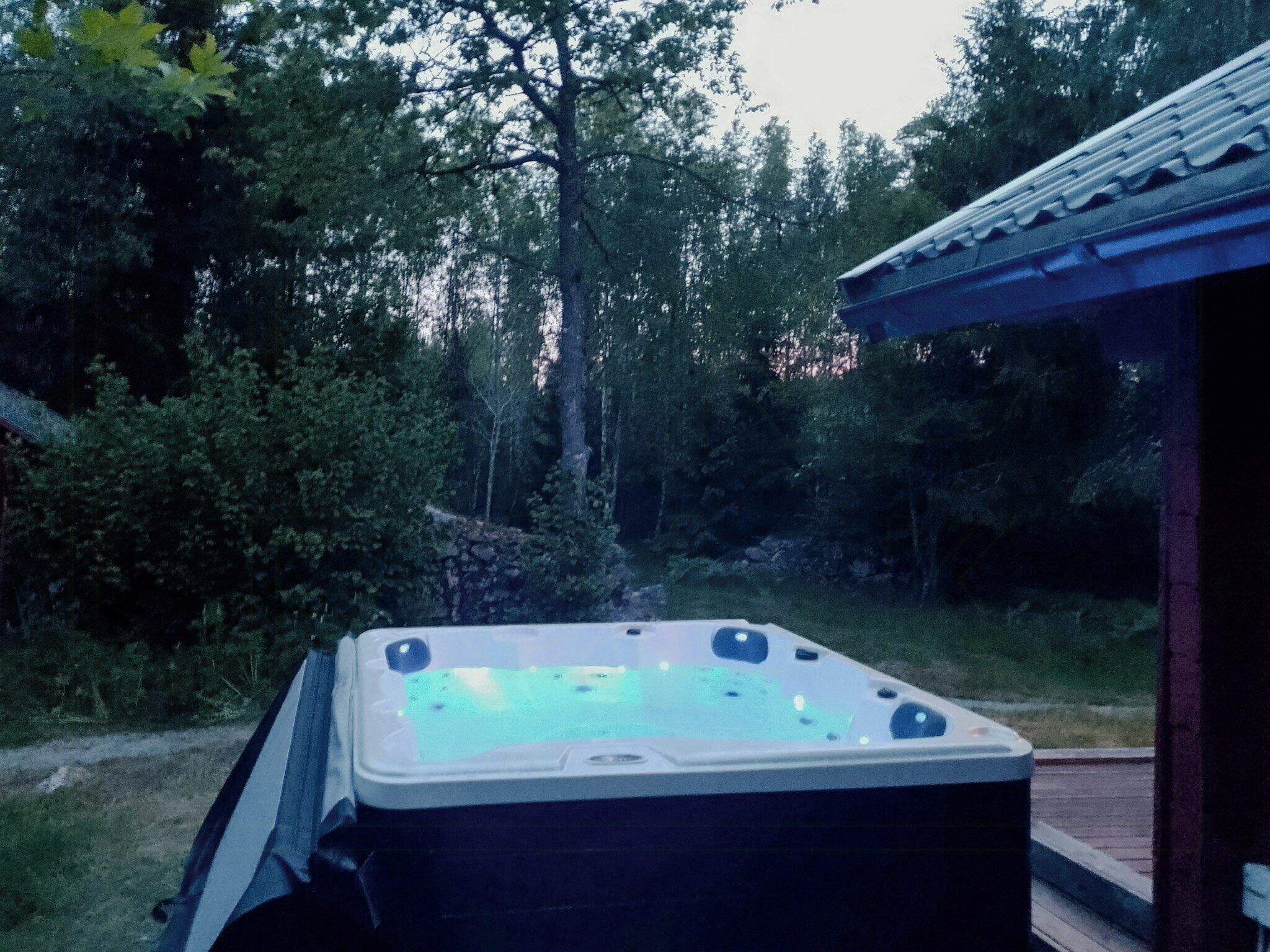 Un bain à remous situé dans un espace boisé, avec une structure en bois en arrière-plan.