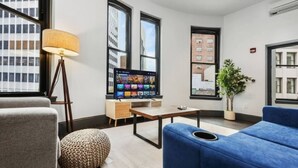 A modern living room with a flat-screen TV, a lamp, a sofa, and a potted plant. - Cozy 1BR Downtown Pittsbu (Pittsburgh)