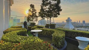A rooftop garden with manicured hedges, a few trees, and a cityscape in the background. - 2 Bed Room Sea View Wonder (Pattaya)