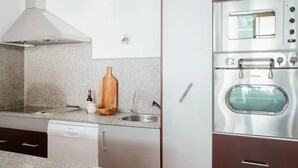 A kitchen with a built-in oven, a stainless steel range hood, and a granite countertop.