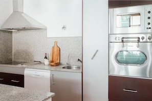 A kitchen with a built-in oven, a stainless steel range hood, and a granite countertop.