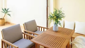 A wooden table with four chairs, a potted plant, and a white pillow on the right.