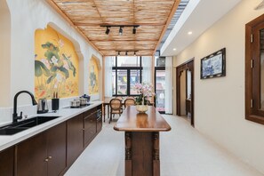 A modern kitchen with a wooden island, a sink, and a dining area with chairs. - Lily Hidden Homestay Spacious 150m² 2BR near Hoan Kiem Lake (Hanoi, Vietnam)
