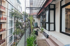A narrow courtyard with a metal fence, potted plants, and a water tank. - Lily Hidden Homestay Spacious 150m² 2BR near Hoan Kiem Lake (Hanoi, Vietnam)