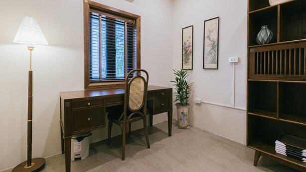 Una sala de estudio con escritorio, silla, lámpara, ventana y estantería.