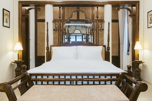 A large bed with a wooden frame and white bedding, flanked by two wooden nightstands with lamps, in a room with a traditional architectural design. - Lily Hidden Homestay Spacious 150m² 2BR near Hoan Kiem Lake (Hanoi, Vietnam)