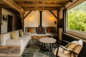 Ein gemütliches Interieur mit Steinboden, Kamin, Sofa und Tisch.
