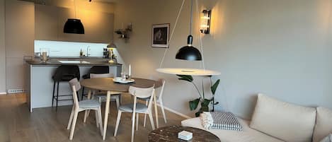 Een moderne woonkamer met een bank, een ronde salontafel en een eethoek met stoelen en een tafel.