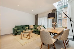 A modern living room with a green sofa, a round coffee table, and a dining table with chairs. - Fahana Canteras (LAS PALMAS DE GRAN CANARIA)