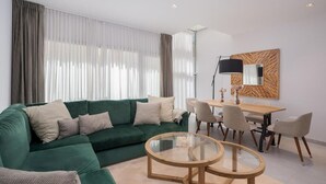 A modern living room with a green sofa, a glass coffee table, and a dining area with chairs and a table. - Fahana Canteras (LAS PALMAS DE GRAN CANARIA)