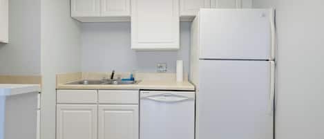 A kitchen with white cabinets, a sink, a dishwasher, and a refrigerator.