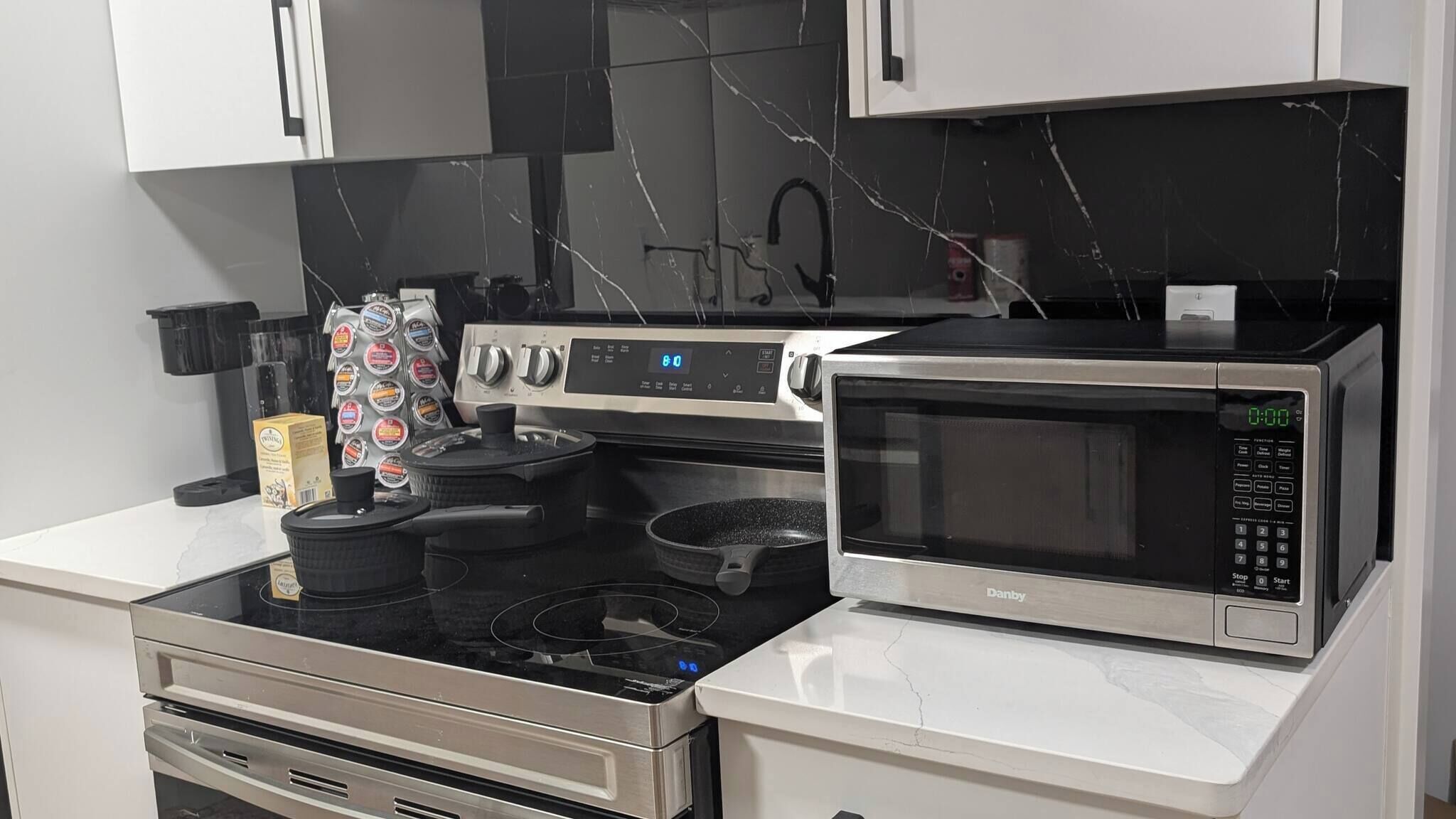 A kitchen with a stove, microwave, and a coffee machine.