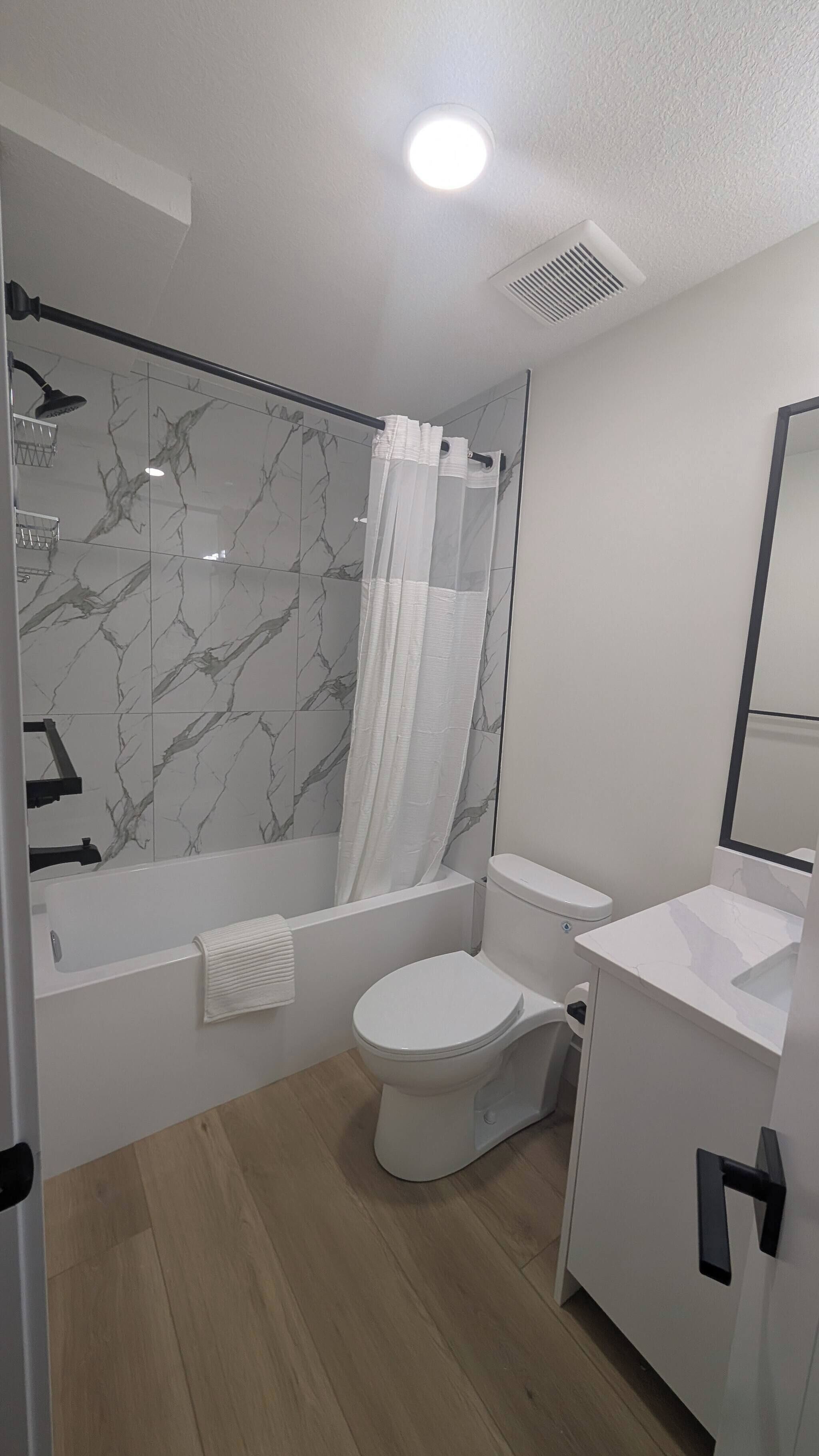 A modern bathroom with a shower, toilet, and sink.