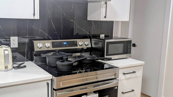 A kitchen with a stove, microwave, and oven.