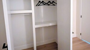 Un vestidor con suelo de madera, paredes blancas y una puerta con picaporte negro.
