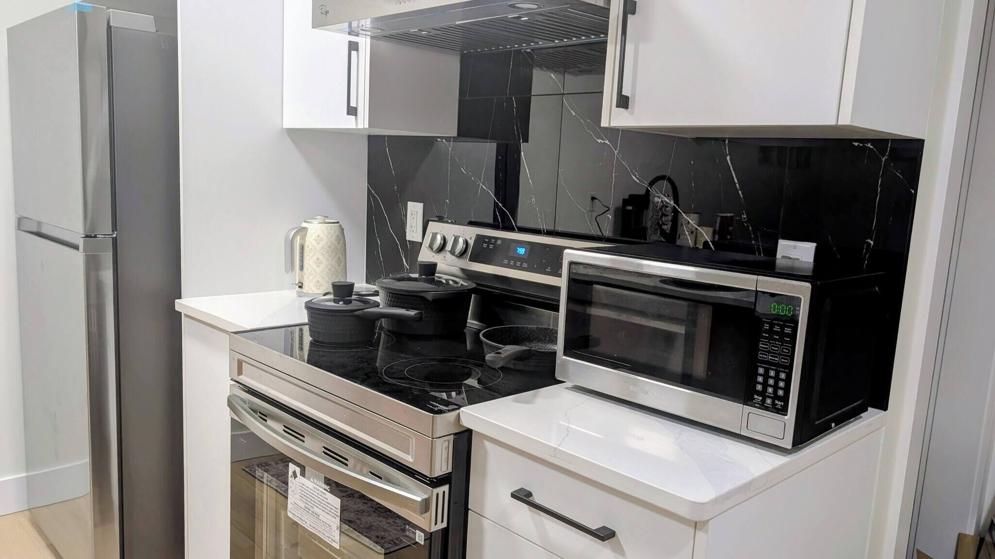 A modern kitchen with stainless steel appliances, including a refrigerator, oven, stove, and microwave.