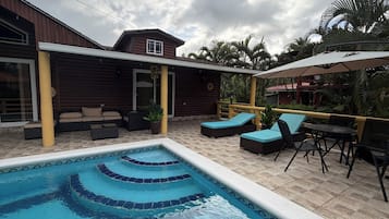 A swimming pool with tiered steps, outdoor seating, and a covered patio area.