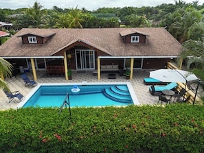 A two-story house with a swimming pool, outdoor furniture, and a covered patio area.