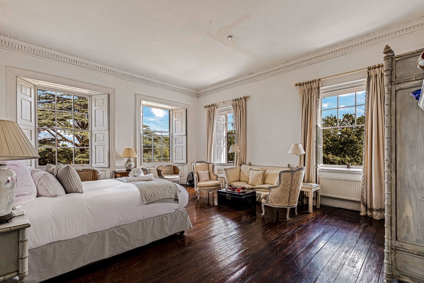 A classic room with a large bed, two armchairs, a small table, and a window with curtains.