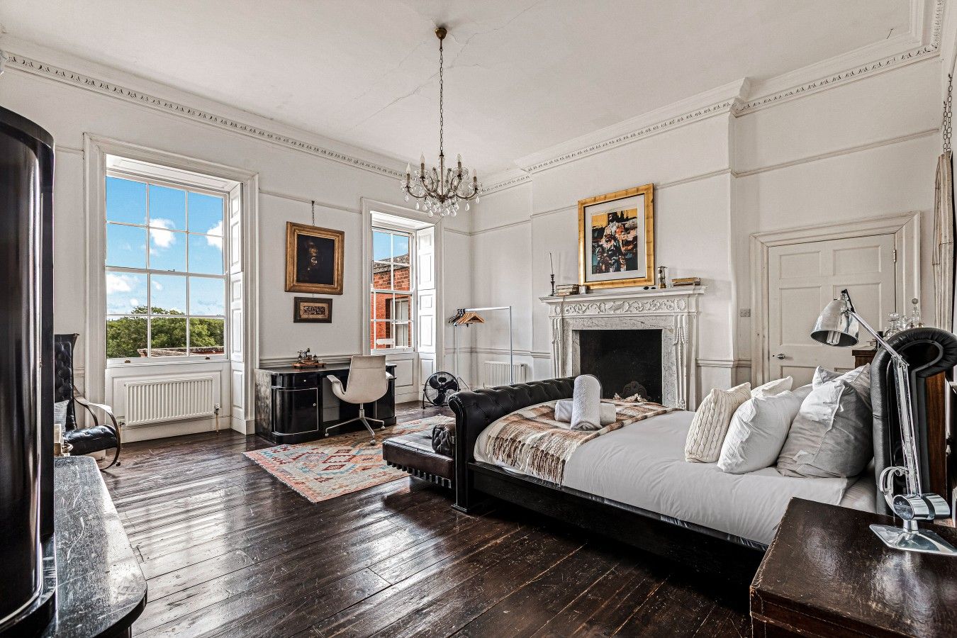 Une pièce spacieuse avec un grand lit, une cheminée et un bureau avec une chaise.